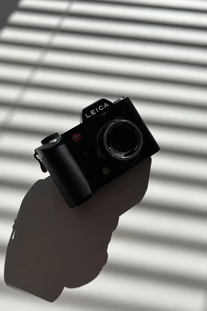 Schwarze Leica-Vollformatkamera mit Festbrennweite im Streiflicht einer Jalousie